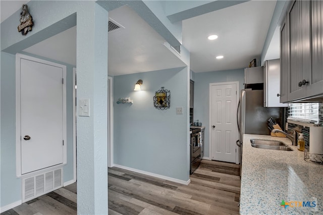 kitchen featuring light stone countertops, sink, stainless steel range with electric stovetop, and light hardwood / wood-style flooring