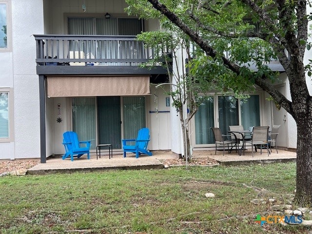 rear view of property with a patio area, a yard, and a balcony