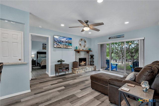 living room with a stone fireplace, hardwood / wood-style flooring, and ceiling fan