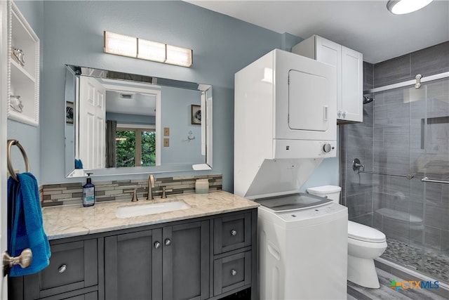 bathroom with toilet, hardwood / wood-style floors, decorative backsplash, vanity, and stacked washer and dryer