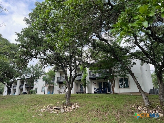 view of front of home with central AC unit and a front yard