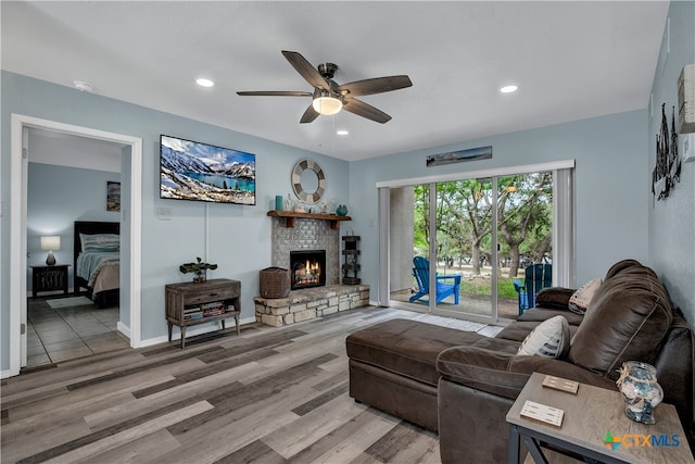 living room with a fireplace, wood-type flooring, and ceiling fan