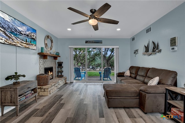 living room featuring a stone fireplace, hardwood / wood-style flooring, and ceiling fan