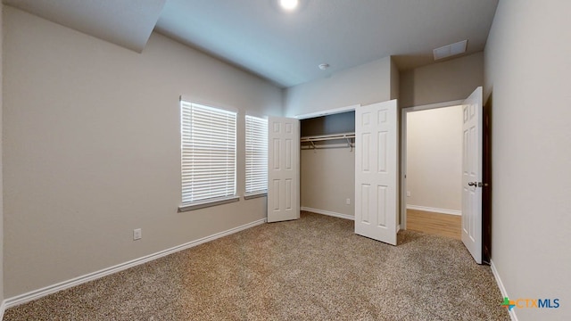 unfurnished bedroom featuring a closet and light colored carpet