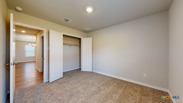 unfurnished bedroom with hardwood / wood-style floors, a closet, and a notable chandelier