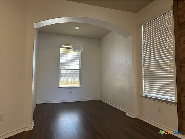 unfurnished room featuring dark hardwood / wood-style floors and an inviting chandelier