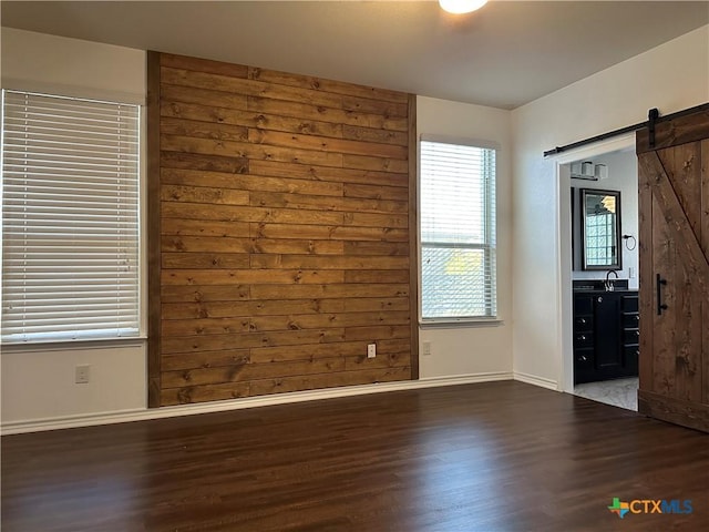 unfurnished bedroom with a barn door and hardwood / wood-style flooring