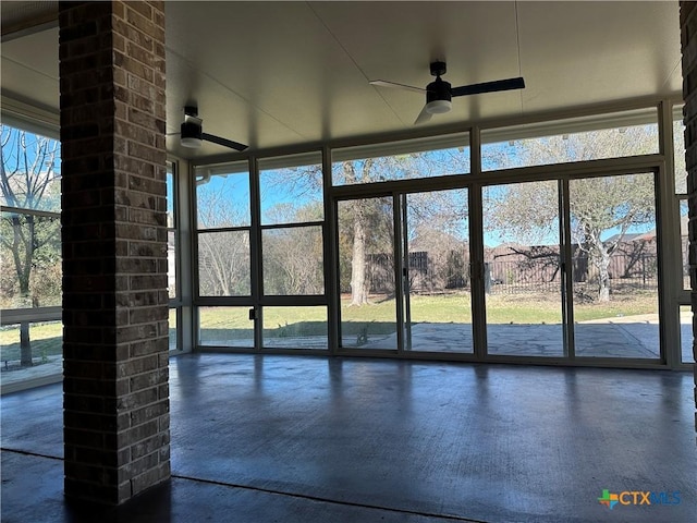 unfurnished sunroom featuring ceiling fan and plenty of natural light