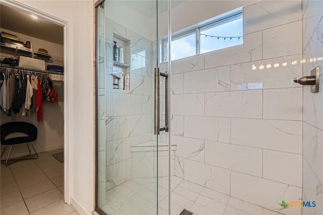 bathroom with a shower stall, a spacious closet, and tile patterned flooring