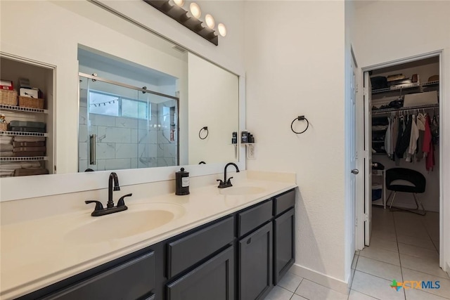 bathroom with double vanity, tile patterned floors, a sink, and a shower stall