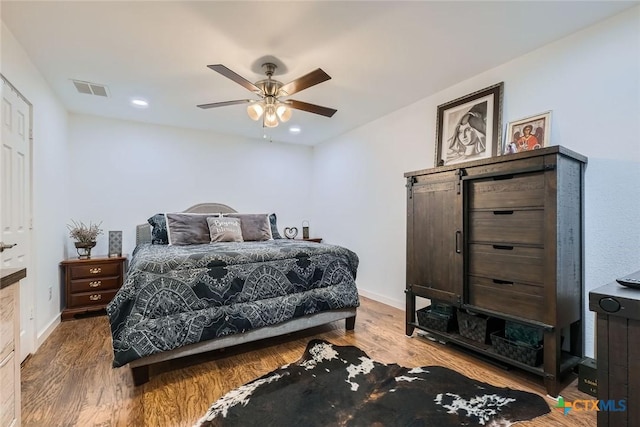 bedroom with wood finished floors, visible vents, and baseboards