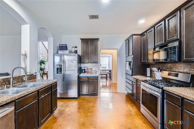 kitchen featuring dark brown cabinetry, stainless steel appliances, a sink, visible vents, and finished concrete flooring