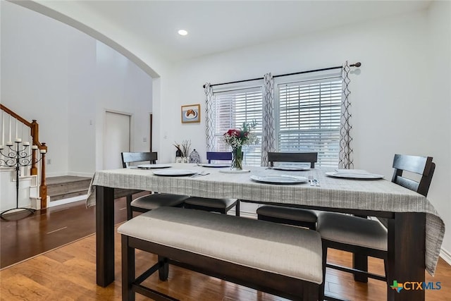 dining area with arched walkways, wood finished floors, stairs, and recessed lighting