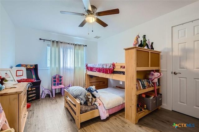 bedroom with a ceiling fan, visible vents, and wood finished floors