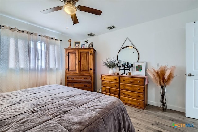 bedroom with baseboards, light wood-style flooring, visible vents, and a ceiling fan