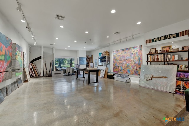 recreation room featuring concrete flooring and rail lighting