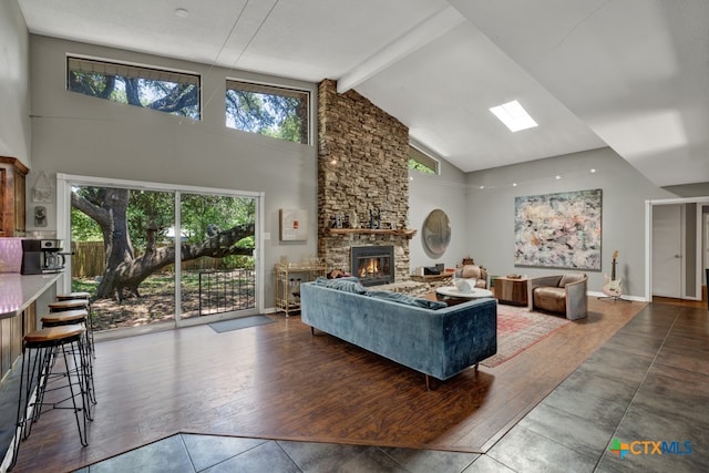 living room featuring hardwood / wood-style floors, a stone fireplace, plenty of natural light, and high vaulted ceiling