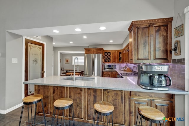 kitchen featuring sink, kitchen peninsula, appliances with stainless steel finishes, a kitchen bar, and backsplash