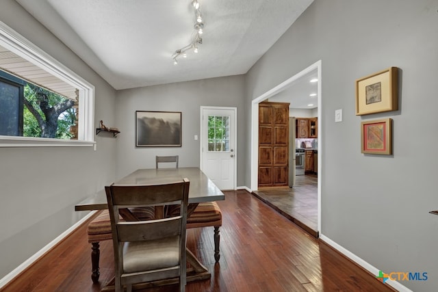 dining area featuring dark hardwood / wood-style flooring, vaulted ceiling, and a textured ceiling