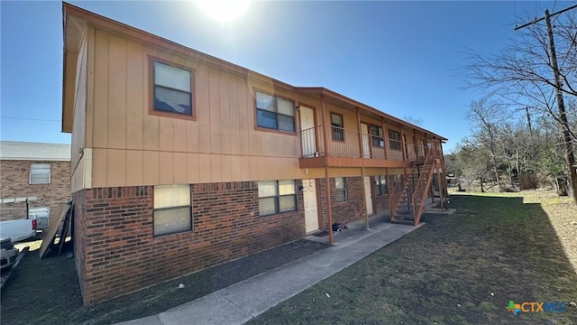 rear view of property featuring stairway and brick siding