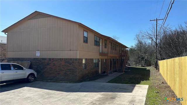 view of side of home featuring brick siding and fence