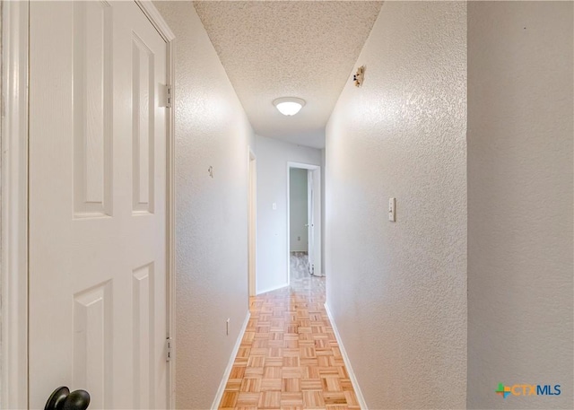 hallway featuring light parquet flooring and a textured ceiling