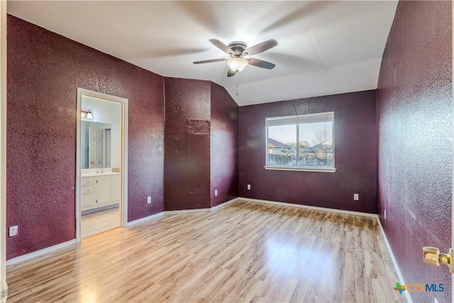 empty room with ceiling fan, lofted ceiling, light hardwood / wood-style flooring, and sink