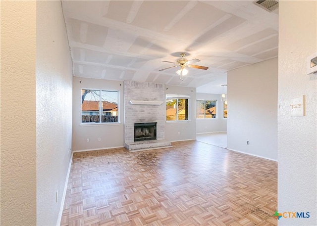 unfurnished living room with ceiling fan, light parquet flooring, and a fireplace