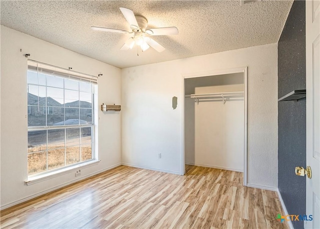 unfurnished bedroom featuring ceiling fan, a textured ceiling, a closet, and light hardwood / wood-style flooring