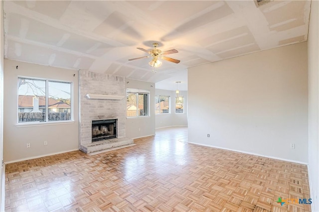 unfurnished living room featuring ceiling fan, light parquet floors, and a large fireplace