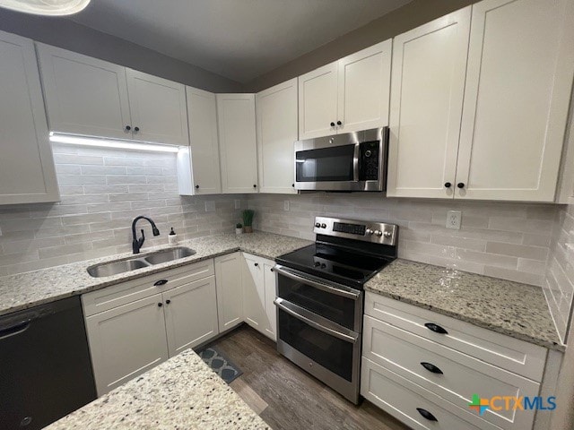 kitchen featuring light stone counters, sink, tasteful backsplash, white cabinetry, and appliances with stainless steel finishes