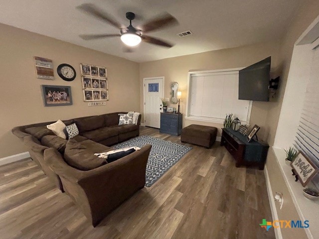 living room featuring dark wood-type flooring and ceiling fan