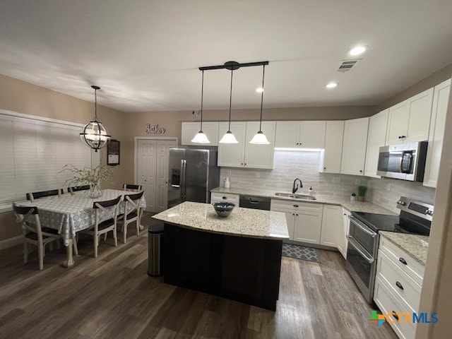 kitchen with stainless steel appliances, white cabinetry, hanging light fixtures, a center island, and dark wood-type flooring