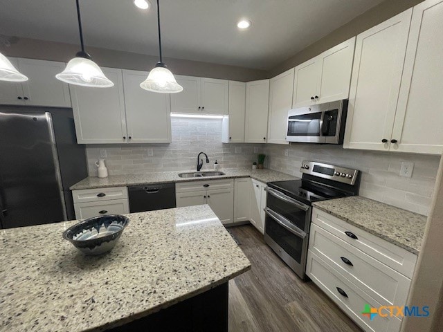 kitchen featuring stainless steel appliances, dark hardwood / wood-style floors, pendant lighting, sink, and white cabinets