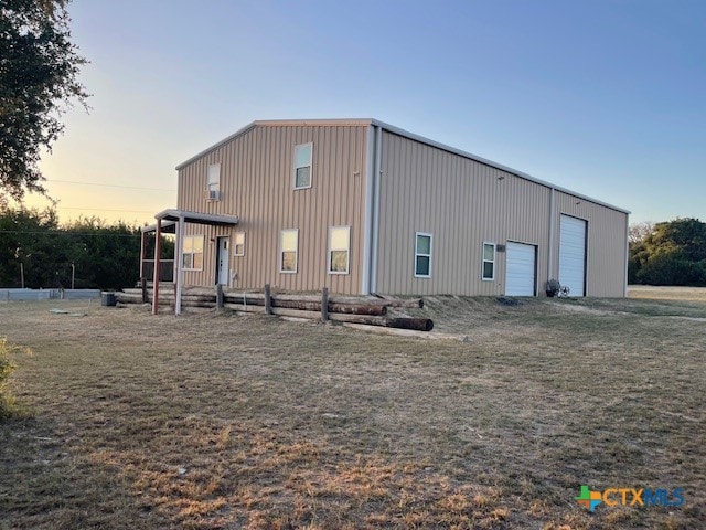 back house at dusk featuring a garage