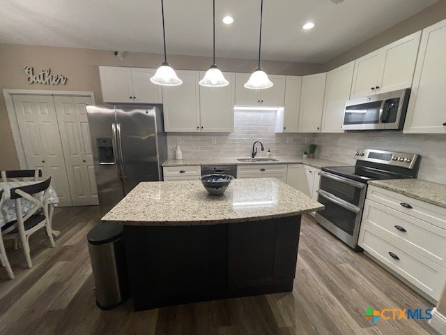 kitchen with hanging light fixtures, white cabinetry, appliances with stainless steel finishes, and a center island