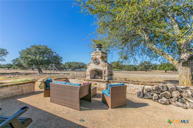 view of patio with an outdoor living space with a fireplace and a rural view