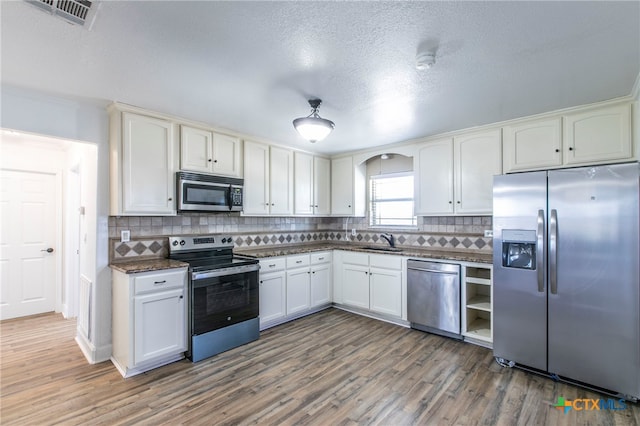 kitchen with sink, appliances with stainless steel finishes, tasteful backsplash, white cabinets, and dark wood-type flooring