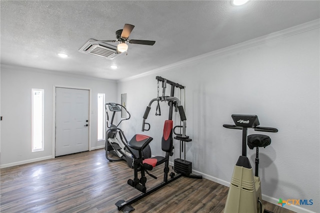 workout area featuring dark wood-type flooring, ceiling fan, a textured ceiling, and crown molding