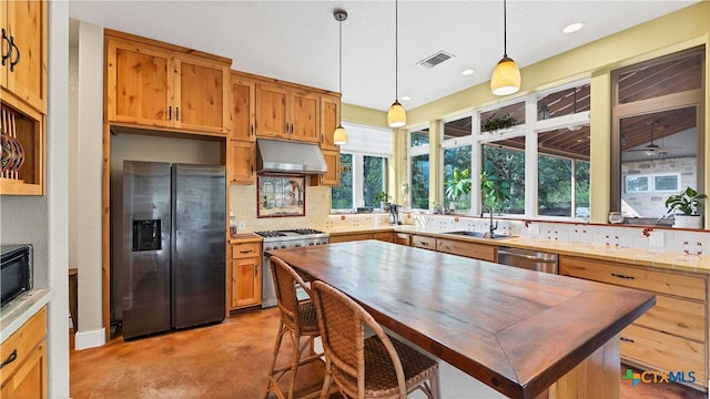 kitchen with tasteful backsplash, appliances with stainless steel finishes, hanging light fixtures, sink, and a center island