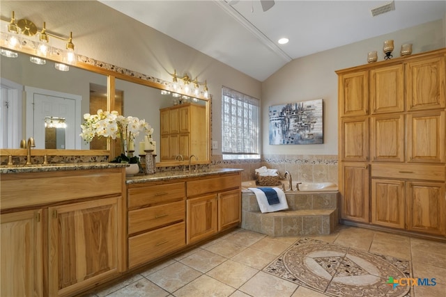 bathroom featuring tile patterned floors, tiled tub, vanity, and lofted ceiling