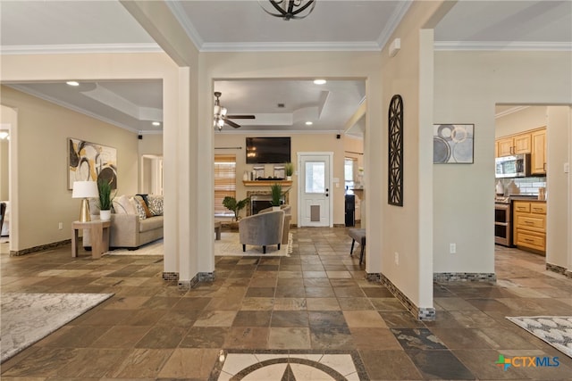 entrance foyer featuring a tray ceiling, ceiling fan, and ornamental molding