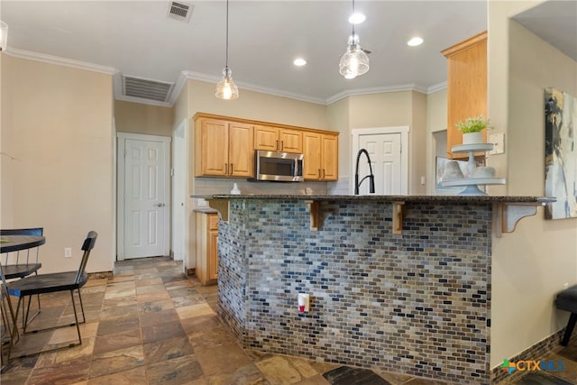 kitchen featuring kitchen peninsula, a kitchen breakfast bar, hanging light fixtures, and ornamental molding