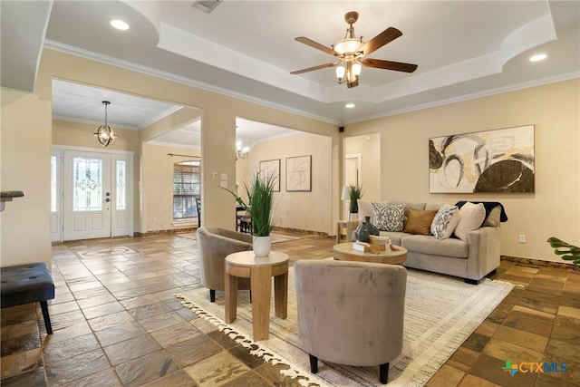 living room featuring ceiling fan with notable chandelier, a raised ceiling, and crown molding