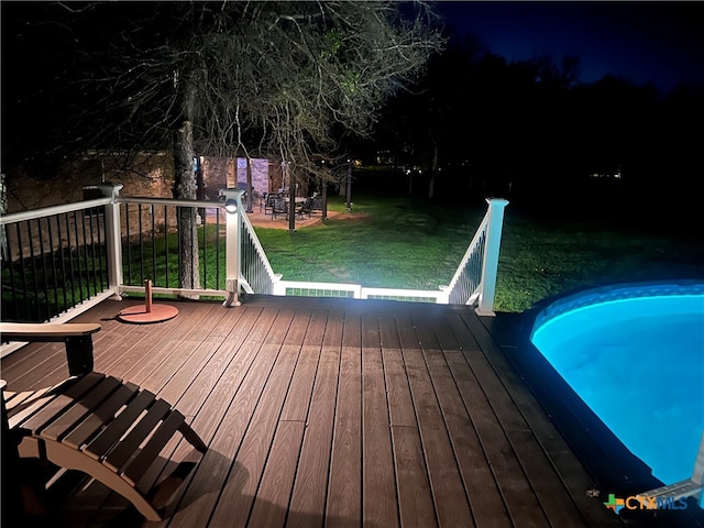 deck at night featuring a yard