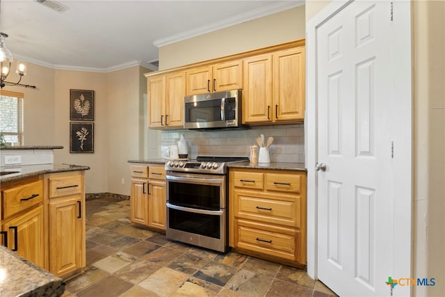 kitchen featuring dark stone counters, an inviting chandelier, decorative backsplash, ornamental molding, and stainless steel appliances