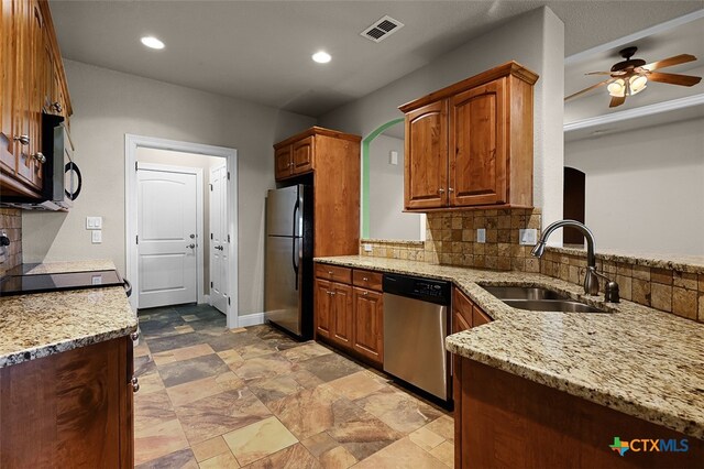 kitchen with stainless steel appliances, sink, backsplash, and light stone counters