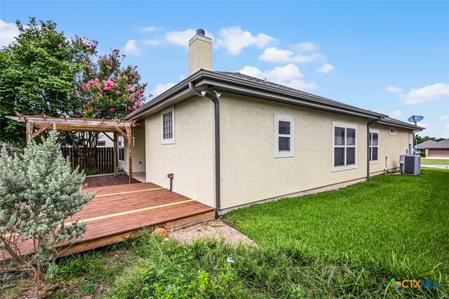 rear view of house with a wooden deck, a yard, and central AC