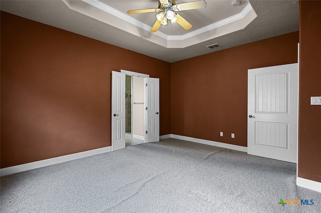 empty room featuring ceiling fan, carpet flooring, a raised ceiling, and ornamental molding