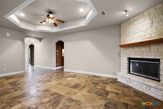 unfurnished living room featuring a fireplace, ceiling fan, and a raised ceiling